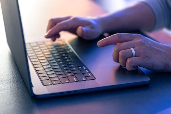 Hospitality professional using a laptop to manage EPOS back office operations and business data.